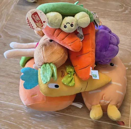 A pile of cuddly plush carrots with a pod of cuddly peas on top