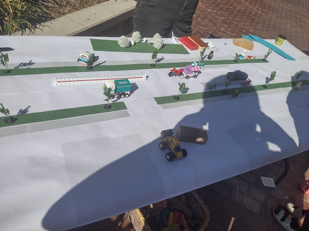 Toy cars and trees laid out on a table to model a street