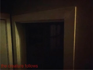 dim image of a dark doorway with the words "the creature follows" in red